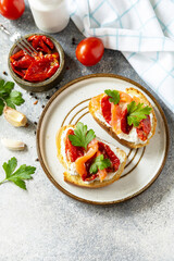Open sandwiches or bruschetta with salted salmon, cheese and sun dried tomato on a stone table. Healthy food, seafood.