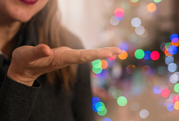 Empty female hand holding palm. Blurred Christmas tree on background. Christmas card with space for text