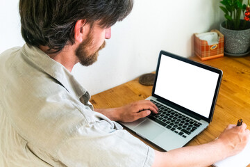 bearded man is working on a laptop. Laptop screen mockup. Selective focus