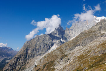 Fototapeta na wymiar Mountain Range of the Italian Alps on a Sunny Summer Day, close-up view of the Rocks and Blue Sky with Clouds