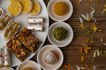 Mix indian sweets like kaju roll dryfruits barfi mango peda served in a plate