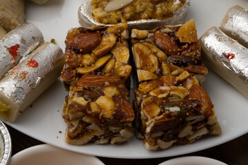 Mix indian sweets like kaju roll dryfruits barfi mango peda served in a plate