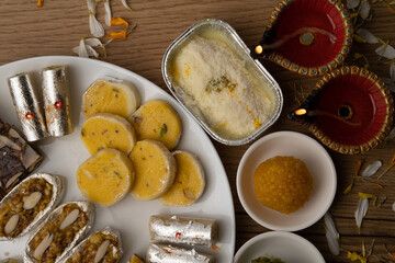 Mix indian sweets like kaju roll dryfruits barfi mango peda served in a plate