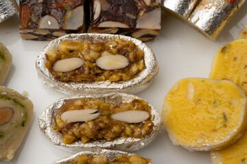 Mix indian sweets like kaju roll dryfruits barfi mango peda served in a plate