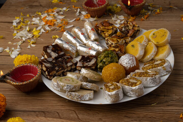 Mix indian sweets like kaju roll dryfruits barfi mango peda served in a plate