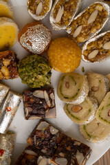 Mix indian sweets like kaju roll dryfruits barfi mango peda served in a plate