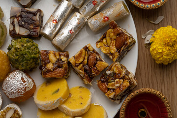 Mix indian sweets like kaju roll dryfruits barfi mango peda served in a plate