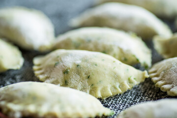 Raw dumplings from dough with herbs, dill and parsley.