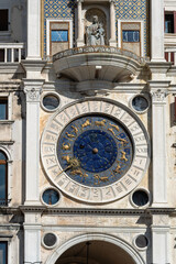 Fototapeta na wymiar Saint Mark's Clock Tower in Saint Mark's Square (Piazza San Marco), Venice, vintage clock with golden zodiac signs and Roman dial, early Italian Renaissance architectural monument in Venice