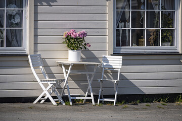 Fototapeta na wymiar Flowers, table and chairs in the sunshine, Kabelvag, Lofoten Islands, Norway