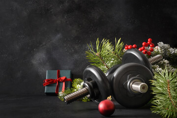 Christmas sport composition with two sports dumbbells, gift, evergreen branches on black...