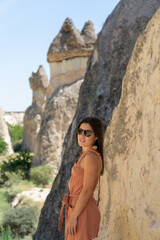 Young woman with sunglasses visiting pasabag valley with typical rock formations of the cappadocia area in turkey