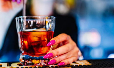 woman hand bartender making negroni cocktail in bar