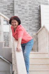 Happy optimistic senior woman leaning on staircase railing outdoors.