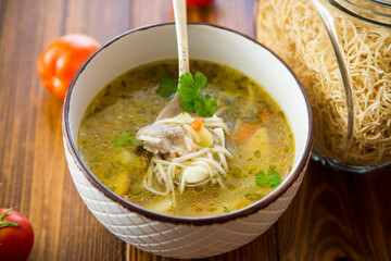 Chicken noodle soup with parsley and vegetables in a white plate