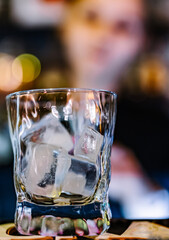 Ice cube in an empty glass on a bar counter in bar or pub