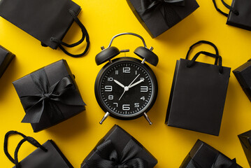 Black friday shopping concept. Top view photo of black alarm clock paper bags and gift boxes with...