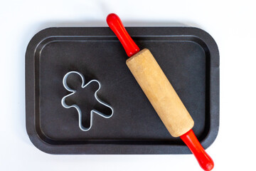 Wooden rolling pin for children with christmas metal molds on the table