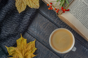 Colorful autumn maple leaves, book and cup of coffee on wooden texture, top view.