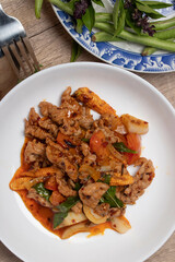 Pork stir fried in chili paste with tomatoes and onions in a white dish