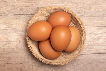 Chicken eggs in bamboo basket on wooden background