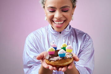 Happy birthday donut, black woman with cupcake candles and hands holding sweet dessert in New York. Anniversary celebration cake, young cool girl smile in studio with pink background and solo party