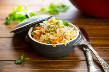 Braised cabbage with carrots, onions and herbs in a ceramic bowl