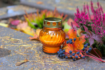 An orange candle on a grave in a cemetery on an autumn day. All Saints Day. Copy space, shallow...