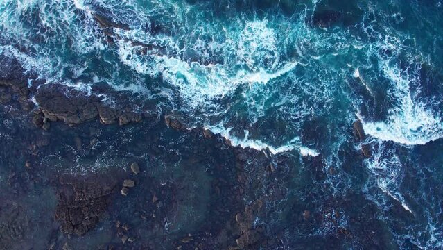 Bird s eye Shot Of Soft Waves Crashing Between Small Rocks In Blue Sea