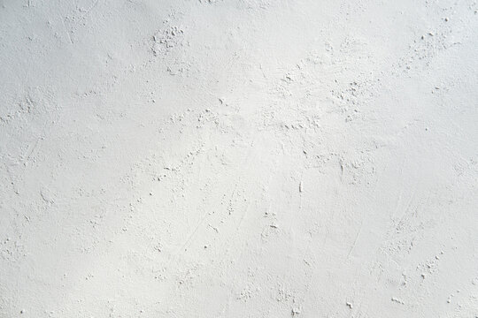 White gray plastered wall background. White concrete background close up. Abrasive white cement background in the rays of the sun with shadows