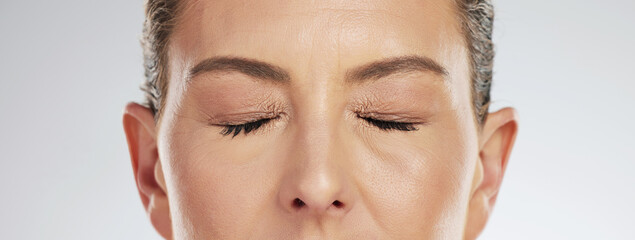 Elderly, woman and makeup of closed eyes against studio background for cosmetics, anti aging or...