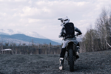 Female wearing moto equipment riding enduro motorcycle  through off-road in mountains