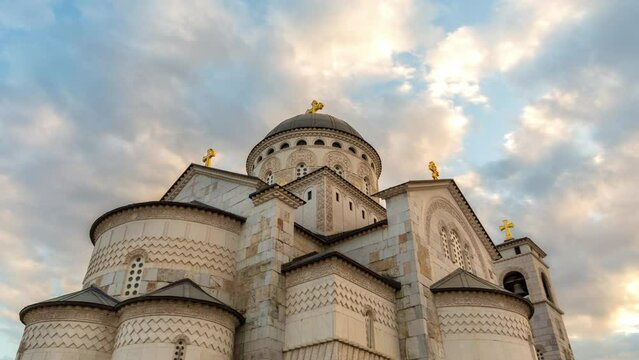 Christian church hyper-lapse under dramatic sky. Dome and crosses on an orthodox cathedral. Religious temple - place of worship of Jesus against fast moving clouds. Resurrection of Christ in Podgorica