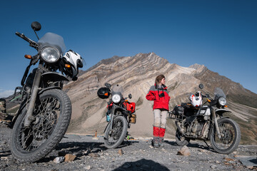 biker female in mountains moto trip resting near off-road motorcycles with amazing mountain background in Himalayas