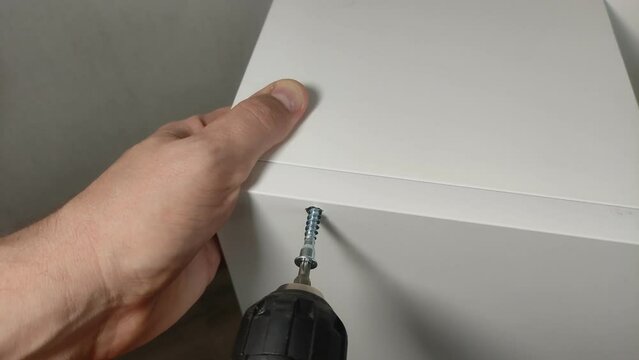 Furniture assembler connects parts of furniture boards with a confirmat and an electric screwdriver
