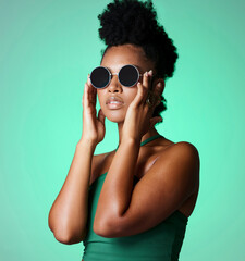 Fashion, black woman and glasses with a model in studio on a green background with vintage or retro...