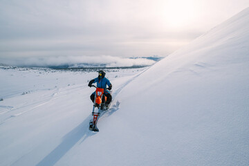 Snowbike rider riding on steep snowy slope. Modify motorcycle with ski and special snowmobile-style...