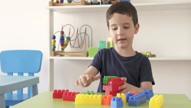 4k video footage of a little boy playing with colourful educational toy blocks on the table at preschool or kindergarten. Kid having fun while engaged in creative learning and development