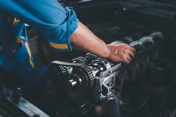 A mechanic is performing engine valve system repairs on a vehicle.