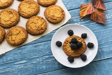 Homemade cookies on a wooden background and autumn fallen leaves. Sweet autumn baking concept.