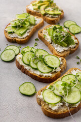 Vegetarian green sandwiches with avocado and cucumber with microgreens on a light background