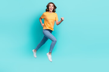 Fototapeta na wymiar Full length photo of excited sweet girl dressed yellow t-shirt jumping high running fast isolated teal color background