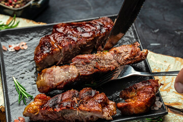 cut the steak with a knife on a dark background. American food concept. banner, menu, recipe place for text, top view