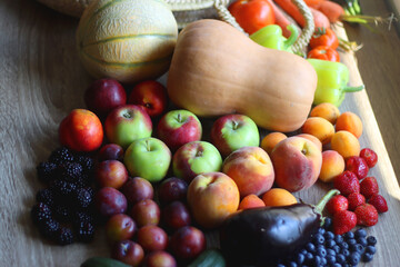 Round straw bag and various healthy fruits and vegetables on wooden background. Selective focus.