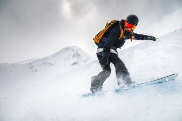 snowboarder quickly descends creating a wave of snow against the backdrop of mountains. ski resort....
