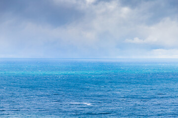 Naklejka na ściany i meble Blue sea is under cloudy sky on a c cloudy day