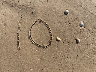 On the beach in the sand is carved the number 10