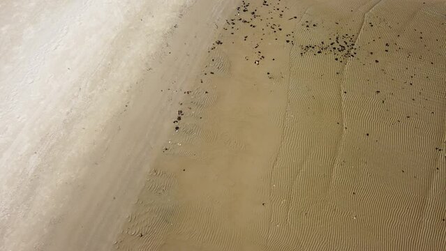 sandy beach shot by drone at a low altitude above, sea waves