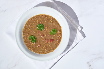 Lentil soup with ingredients on the side, healthy homemade dish.