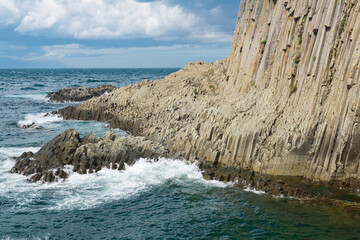 natural landscape with a sheer cliff folded columnar basalt on the seashore